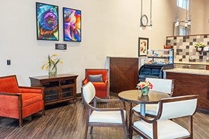 Dining area with snack bar and table and orange club chairs.