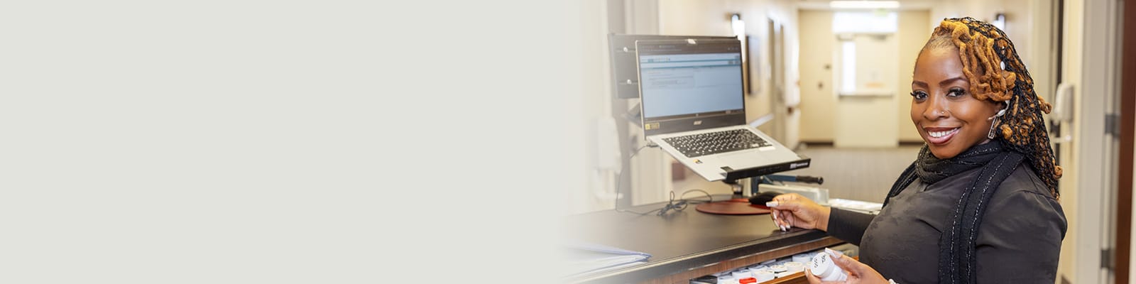 A caregiver standing at the nurses' cart in the hallway at Coal Creek Post Acute
